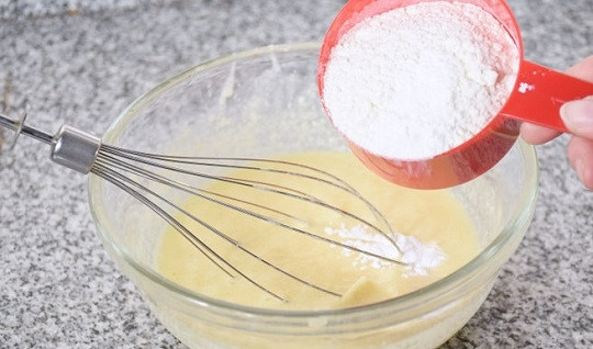 1. Этап. Тесто для кексов в формочках: 4. Всыпьте просеянную муку небольшими порциями и замесите однородное тесто. Если тесто для кексов в формочках в домашних условиях получилось слишком густым, добавьте еще немного йогурта.