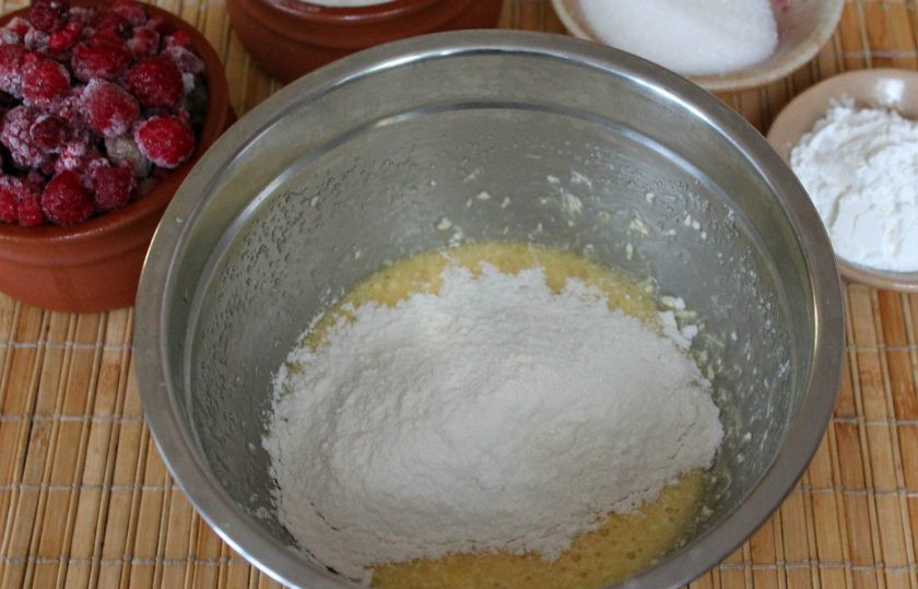 1. Этап. Песочный пирог с малиной: Небольшими порциями добавляем муку и замешиваем тесто.