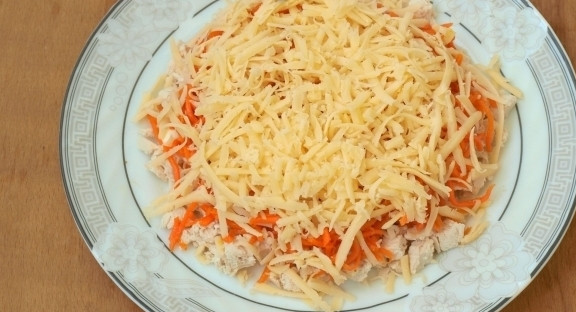 1. Этап. Слоеный салат с корейской морковью: Далее выложите морковь. Сверху натрите сыр на крупной тёрке. Намажьте его майонезом.