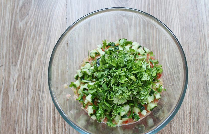 1. Этап. Гаспачо с томатным соком: Добавьте в миску порезанный огурец и зелень.