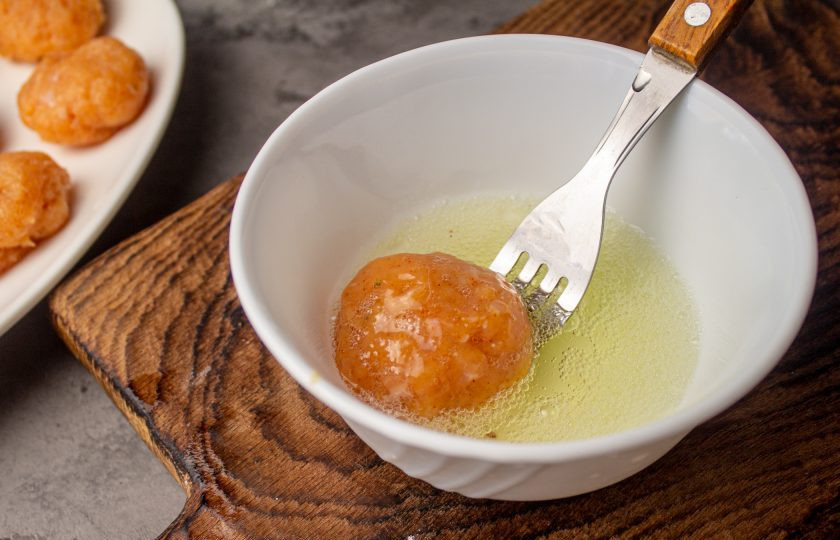 1. Этап. Наггетсы в духовке без масла: Поочередно каждый мясной шарик обмакните в белки.