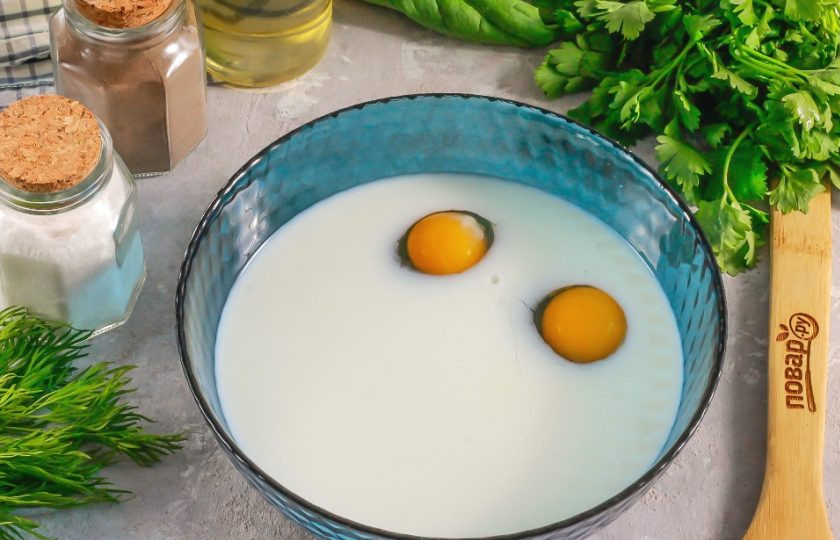 1. Этап. Блинчики шпинатные: В глубокую емкость влейте молоко любой жирности, вбейте куриные яйца и всыпьте соль. Аккуратно все взбейте венчиком.