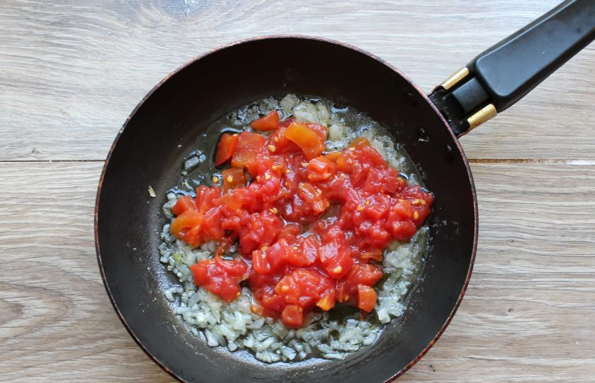 1. Этап. Яичница с консервированными помидорами: Консервированные помидоры порежьте на мелкие кусочки и выложите в сковороду с обжаренным луком. Доведите все до кипения, перемешивая.