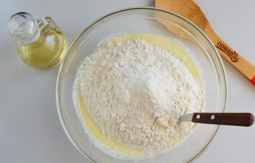 1. Этап. Вкусные пирожки на кефире: Всыпьте муку и разрыхлитель. Начните ложкой замешивать тесто.