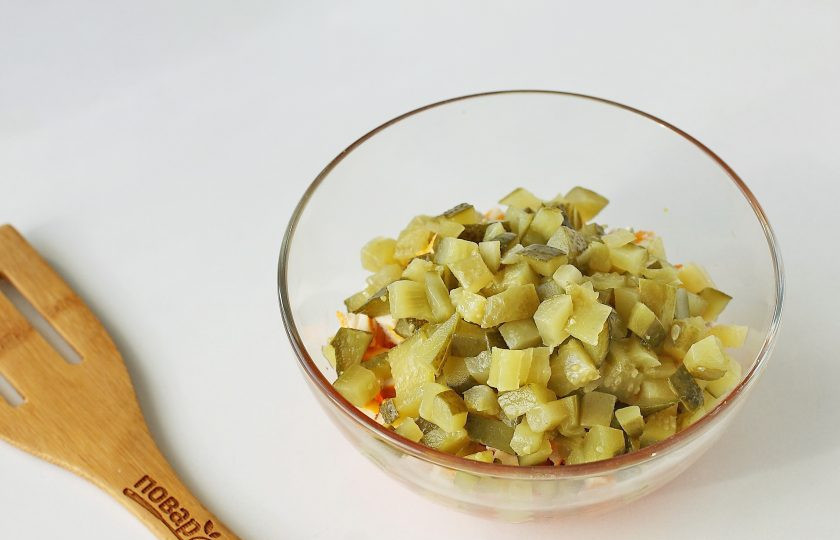 1. Этап. Салат с курицей и кириешками: Огурец нарежьте примерно такими же кубиками, слегка отожмите и добавьте к остальным ингредиентам.