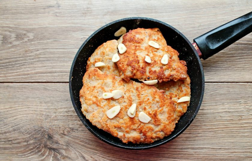 1. Этап. Свинина в льезоне: Выложите обжаренные куски мяса в сковороду и влейте немного воды. Чеснок очистите и порежьте на слайсы, выложите в сковороду. Готовьте на медленном огне под крышкой еще 10-15 минут.