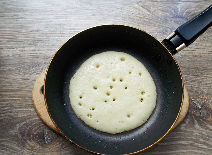 1. Этап. Блины на живых дрожжах: Сковороду нагрейте на среднем огне, смажьте растительным маслом и налейте один половник теста. Готовьте на среднем огне, пока верх не перестанет быть жидким, а нижняя сторона не станет золотистой.