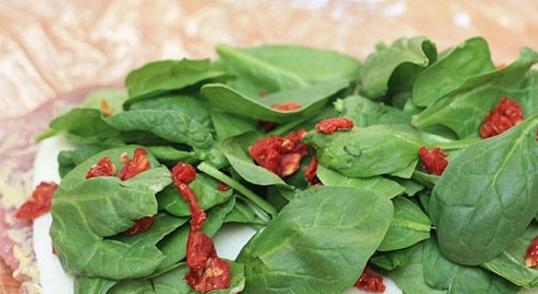 1. Этап. Праздничный рулет из свинины с начинкой: 3. Следом - шпинат и помидоры. Слегка прижмите начинку руками.