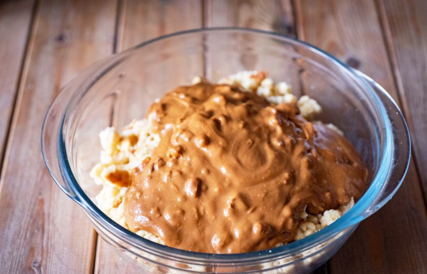 1. Этап. Торт Муравейник с медом: Готовое песочное печенье охладите и поломайте руками на мелкие кусочки, выложите в миску и добавьте к поломанному печенью крем из сгущенки, меда и орехов. Перемешайте все ложкой так, чтобы крем покрыл все кусочки печенья.