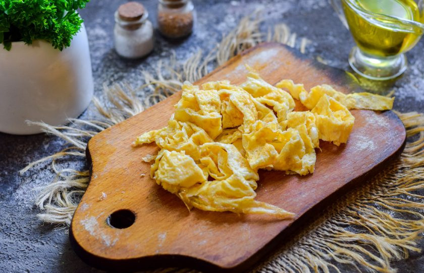 1. Этап. Теплый салат с печенью и омлетом: Яичный блинчик сверните рулетиком и нарежьте полосками.