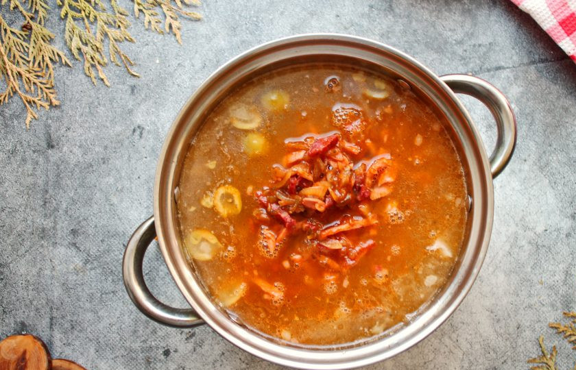 1. Этап. Солянка Московская: Переложите в кастрюлю обжаренную колбасу с овощами. Все перемешайте и доведите до кипения, убавьте огонь и варите в течение 10 минут.