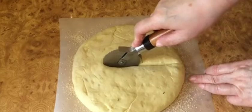 1. Этап. Пшеничный калач Солнышко: 5. Каждую часть округлите, накройте пленкой и оставьте при комнатной температуре на 10 минут. На пергамент равномерно высыпьте овсяные отруби или кунжут. Одну часть теста выложите на отруби и распластайте в толстый круг.