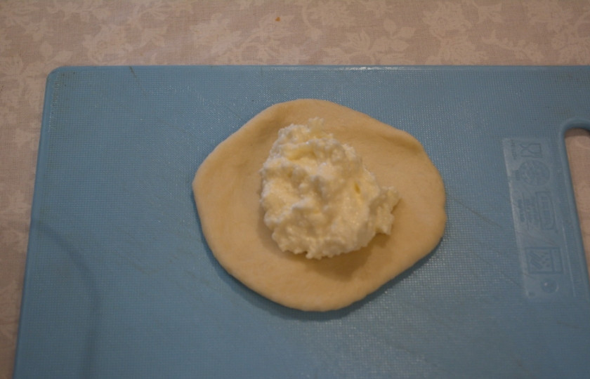 1. Этап. Печеные пирожки из дрожжевого теста: Подготовьте начинку. Смешайте 300 гр творога, 4 ст. ложки сахара (можно больше), 1 яичный белок. Все перемешайте. Из комочка теста сделайте бличик, выложите начинку.