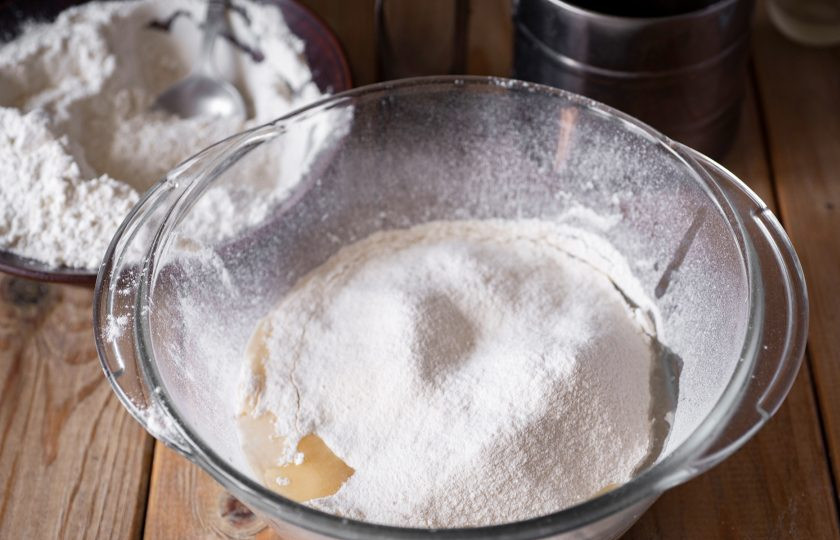 1. Этап. Булочки простые: Просейте муку и залейте растительное масло. Муку лучше всего просеивать небольшими частями: сначала вмешиваете ее ложкой, а затем приступаете к замесу руками.