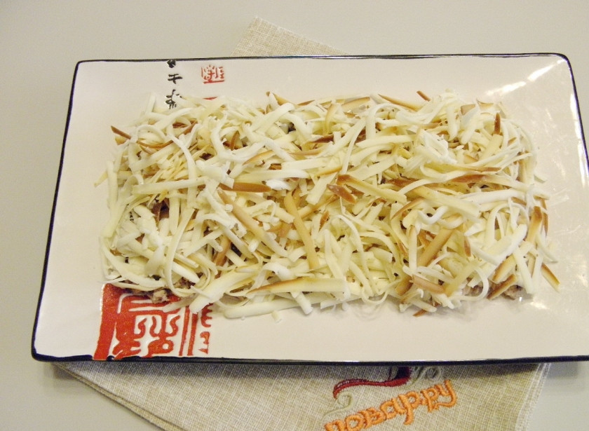 1. Этап. Салат Всем нравится: Колбасный сыр натрите на крупной терке и распределите по салату. Сделайте майонезную сеточку.