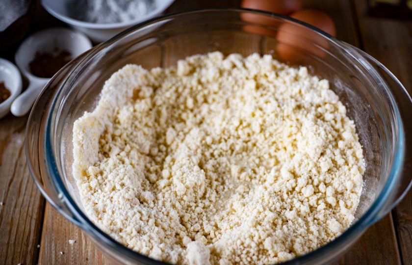 1. Этап. Тыквенный пирог классический: Всю мучную крошку высыпите в миску и добавьте ледяную воду.