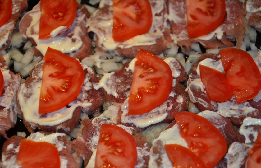 1. Этап. Отбивные из свинины в духовке: 2. Смазываем каждый кусочек небольшим количеством майонеза и выкладываем по ломтику помидора на каждый кусок мяса.