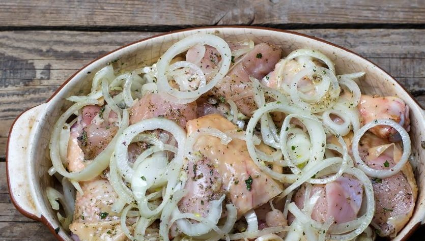 1. Этап. Курятина в духовке: Куски курицы вместе с луком выложите в глубокую посуду. Присыпьте все сушеным орегано, приправьте заправкой. Тщательно все перемешайте и оставьте курицу мариноваться на полчаса.