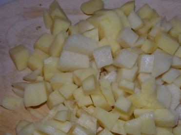 1. Этап. Суп из консервированной кукурузы: Почистим картошку, помоем её и нарежем небольшими кубиками, добавим в кастрюлю с кипящей водой или бульоном.