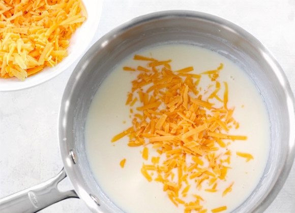 1. Этап. Запеченный картофель с брокколи и сыром: 5. Натрите чеддер на терке. Порционно добавляйте чеддер в кастрюлю, после каждой очередной порции, он должен быть полностью расплавленный.