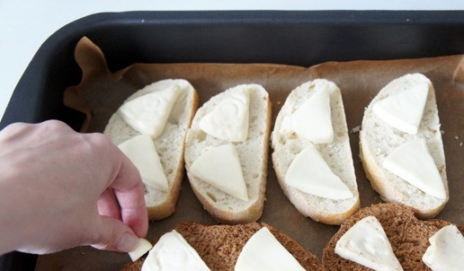 1. Этап. Ассорти брускетт: Вынимаем хлеб. Сыр уже растаял. Второй половинкой зубчика чеснока натираем каждую корочку хлеба. Сыр слегка разминаем вилкой.