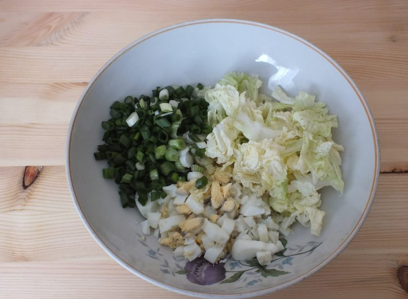 1. Этап. Салат из селедки с сыром: Возьмите глубокий салатник. Положите в него яйца нарезанные кубиком, измельченный зеленый лук, пекинскую капусту.