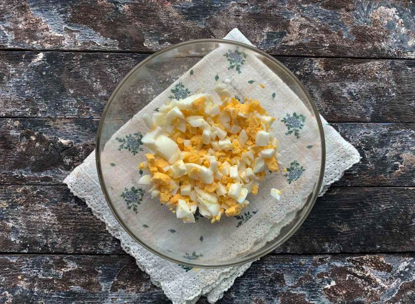 1. Этап. Окрошка с крабовыми палочками: Яйца очистите от скорлупы, мелко нарежьте и выложите в глубокую емкость.