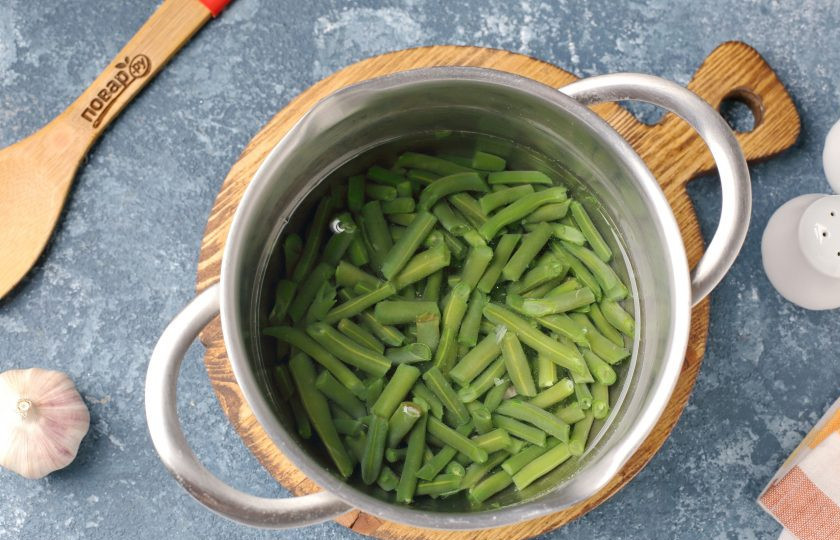 1. Этап. Салат из зеленой фасоли с яйцами: Фасоль отварите в кипящей подсоленной воде в течение 7 минут, затем кипяток слейте, а фасоль залейте ледяной водой.