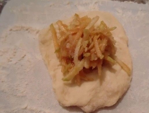 1. Этап. Пончики с яблочной начинкой: 5. От теста (что подошло) отрываю кусочки, руками разминаю каждый в небольшую лепешку, в центр которой выкладываю тертое яблоко, защипываю плотно начинку.