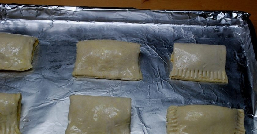 1. Этап. Слойки с куриной начинкой: 3. На противень для выпекания разместите пирожки, смажьте их сырым яйцом.