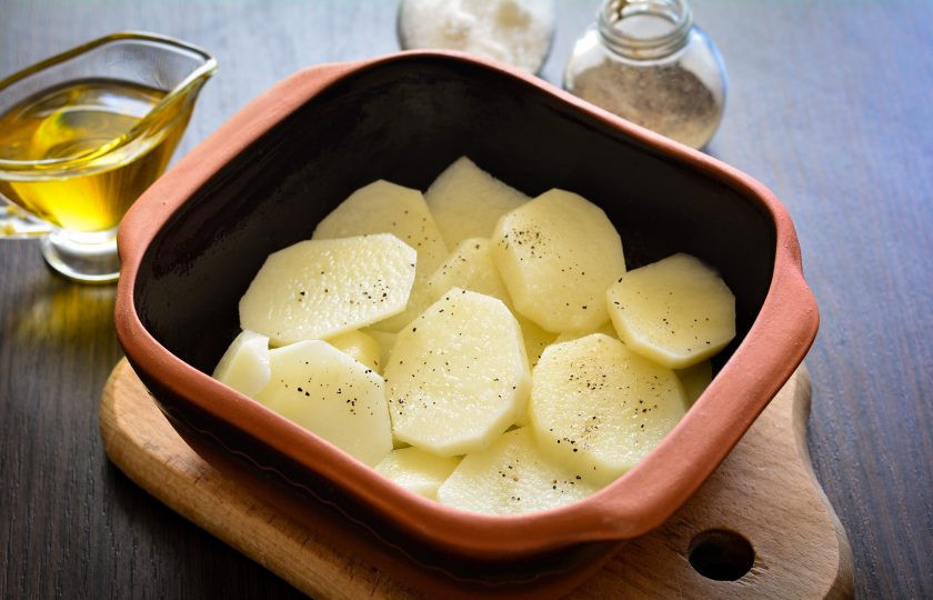 1. Этап. Свиная лопатка с картошкой в духовке: Форму для выпекания смажьте растительным маслом. Половину порции картофеля выложите на дно формы. Картофельный слой немного подсолите и поперчите.