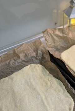 1. Этап. Пицца на дрожжевом тесте: Разделить тесто на две части. Сформировать основы для пиццы. Выложить на противень, застеленный пергаментом