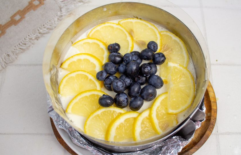 1. Этап. Лимонный чизкейк без выпечки: Достаньте застывший чизкейк из холодильника, украсьте тонко нарезанными дольками лимона и голубикой.