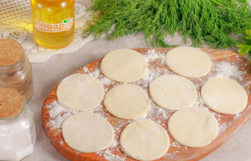 1. Этап. Пельмени с рыбой По-сахалински: Тесто разделите на равные части и раскатайте их в округлые пласты. Обмакивая горлышко стакана в муку, вырежьте из теста круги.