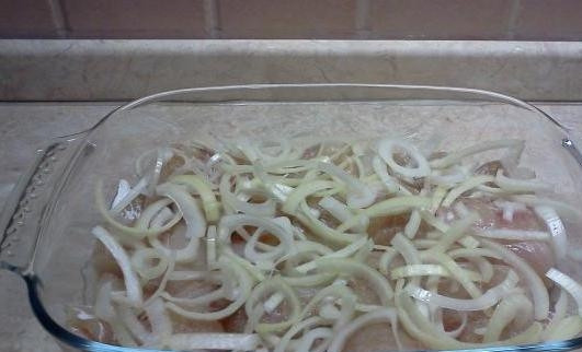 1. Этап. Запеченный минтай: Кольцами и полукольцами нарезаем лук и укладываем сверху на рыбу.