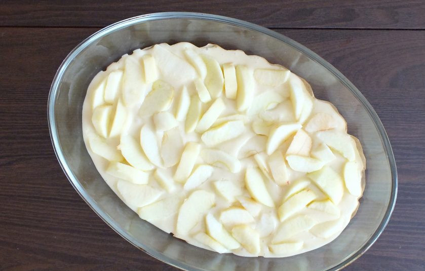 1. Этап. Сахарный пирог с яблоками: Возьмите форму для выпечки. Застелите её дно пекарской бумагой. Вылейте в форму 1/2 часть теста. Сверху распределите яблоки.