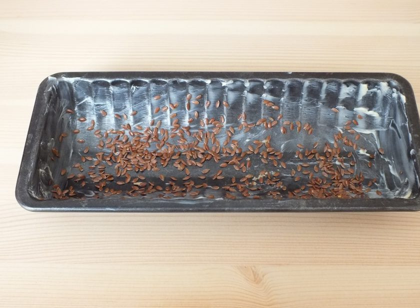 1. Этап. Безглютеновый хлеб в духовке: Подготовьте форму. Смажьте сливочным маслом и обсыпьте 1/2 ст.л. льняного семени.