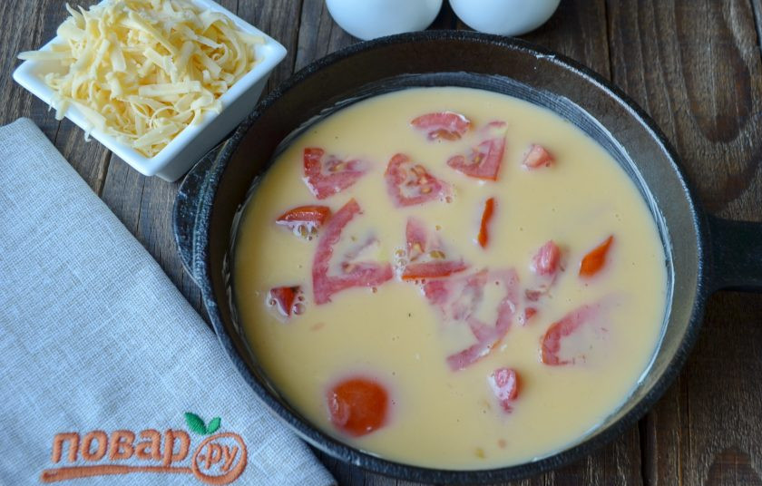 1. Этап. Омлет с помидорами (мастер-класс): Смажьте сковороду сливочным маслом, обжарьте помидоры буквально одну минутку, огонь сильный. Влейте омлет, сверху посыпьте зеленью, распределите тертый сыр. Уменьшите огонь до минимума и томите омлет под крышкой до готовности.