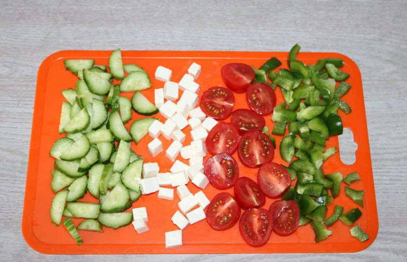 1. Этап. Салат с зелёным болгарским перцем: Нарежьте помидоры черри на половинки, перец и сыр кубиками, огурцы полукольцами.