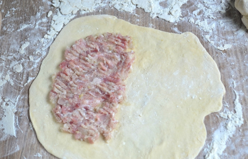1. Этап. Чебуреки классические: Разделите тесто на 6 равный частей. Каждую часть теста раскатайте в тонкий пласт толщиной 2 мм. Условно поделите раскатанный круг пополам, на одну половину положите мясной фарш, оставляя до краев по 2 см.