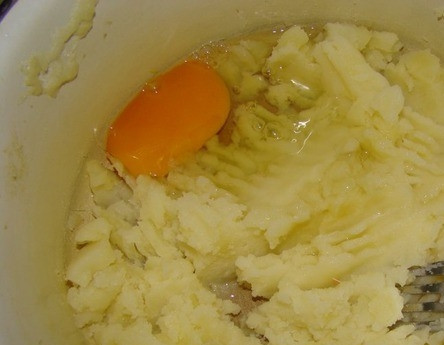 1. Этап. Картофельные котлеты для детей: Картофель вымойте, очистите и отварите до полной готовности в подсоленной воде. Превратите его в пюре при помощи толкушки или блендера, когда он остынет. Вбейте сырое куриное яйцо, посолите и поперчите. Хорошенько перемешайте все ингредиенты.