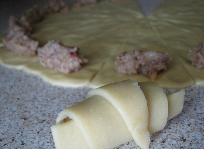 1. Этап. Мутаки: Тем временем мы приготовим начинку, для этого мы взбиваем белки до густой пены, измельченные орехи смешиваем с сахаром. Теперь соединяем белки и орехово-сахарную смесь, перемешиваем. Затем мы вынимаем один шарик из теста и раскатываем так, чтобы у нас получился круг диаметром в 30 сантиметров. Полученный круг нам надо разделить на 16 частей (как пиццу), на широкую часть каждого сегмента выкладываем начинку и сворачиваем сегмент к центру рулетом.