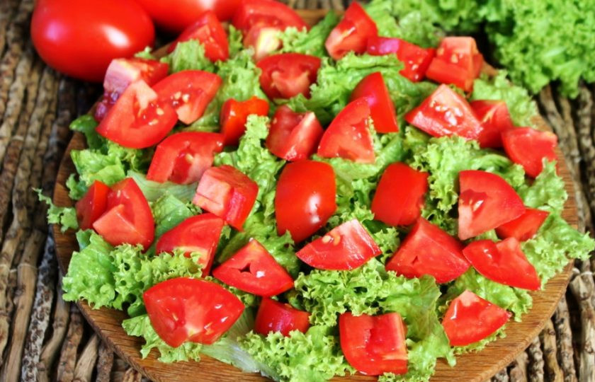 1. Этап. Салат из помидор с курицей и сыром: Режем помидоры и высыпаем их на листья салата.