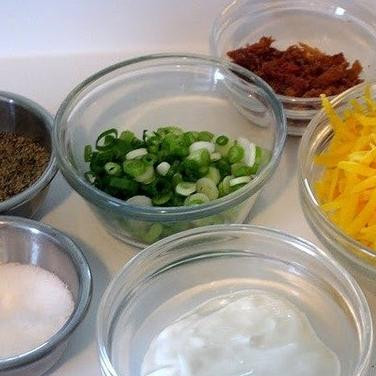 1. Этап. Дважды запеченный картофель: Пока картофель выпекается, готовим вторую часть блюда. Обжариваем в масле ломтики бекона до золотистой корочки, мелко шинкуем зеленый лук и натираем на терке твердый сыр.