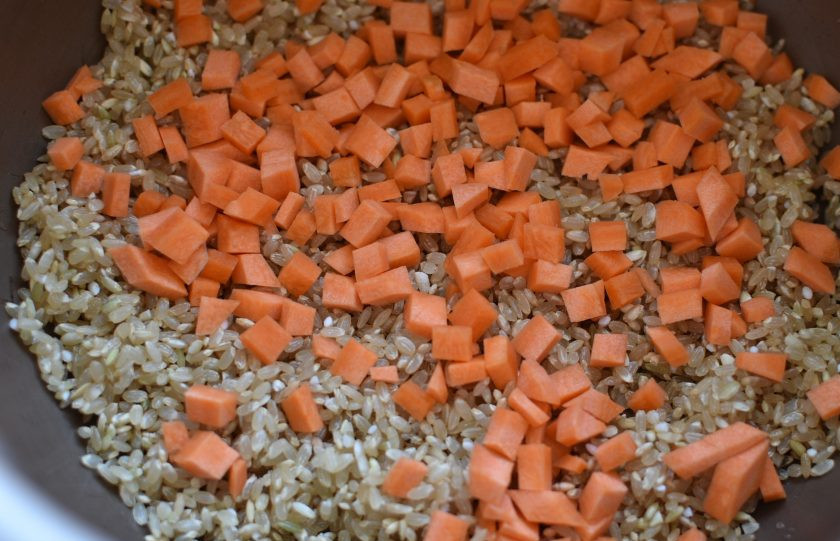 1. Этап. Рис с грибами, овощами и шпинатом: Рис хорошо промойте и обдайте кипятком. Обсушите при помощи сита. Выложите в чашу мультиварки. Сверху выложите нарезанную мелкими кубиками морковь.