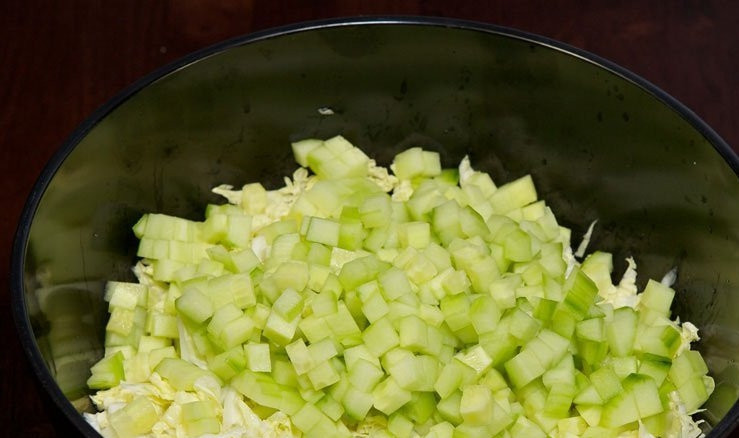 1. Этап. Крабовый салат: Очищенный и нарезанный кубиками огурец добавьте в салатницу.