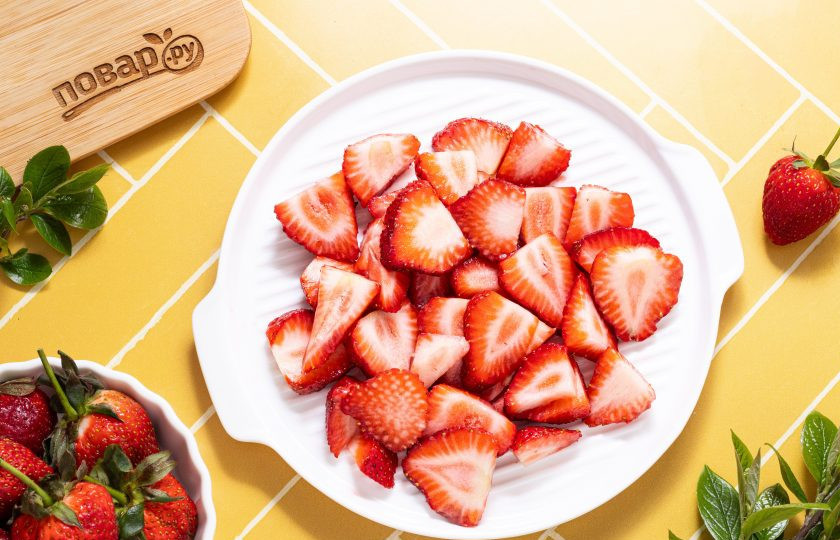 1. Этап. Сок из клубники на зиму: Клубнику тщательно помойте. Отрежьте хвостики, затем нарежьте на ломтики.