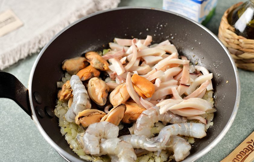 1. Этап. Морепродукты в сливочном соусе: Выложите в сковороду морепродукты, обжарьте вместе с луком и чесноком около минуты.