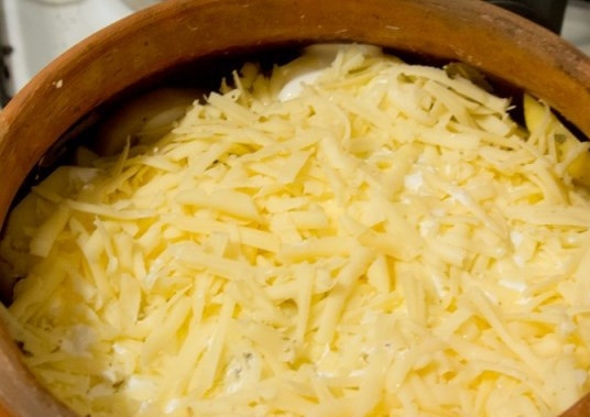 1. Этап. Оленина в горшочке: Полейте картофель сметаной. Также вы можете использовать майонез или же смесь сметаны с майонезом. Твердый сыр натрите на терке и выложите поверх сметаны.