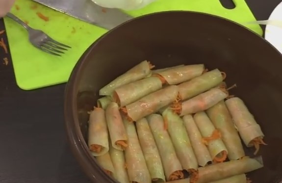 1. Этап. Голубцы с морковкой по-корейски в квашеной капусте: 5. Морковку закладываем на капустный лист с самого узкого края, чтобы она немного выглядывала по бокам. Закручивать голубец надо плотно. Выложите все голубцы в глубокую емкость, сверху заложите целыми капустными листами.